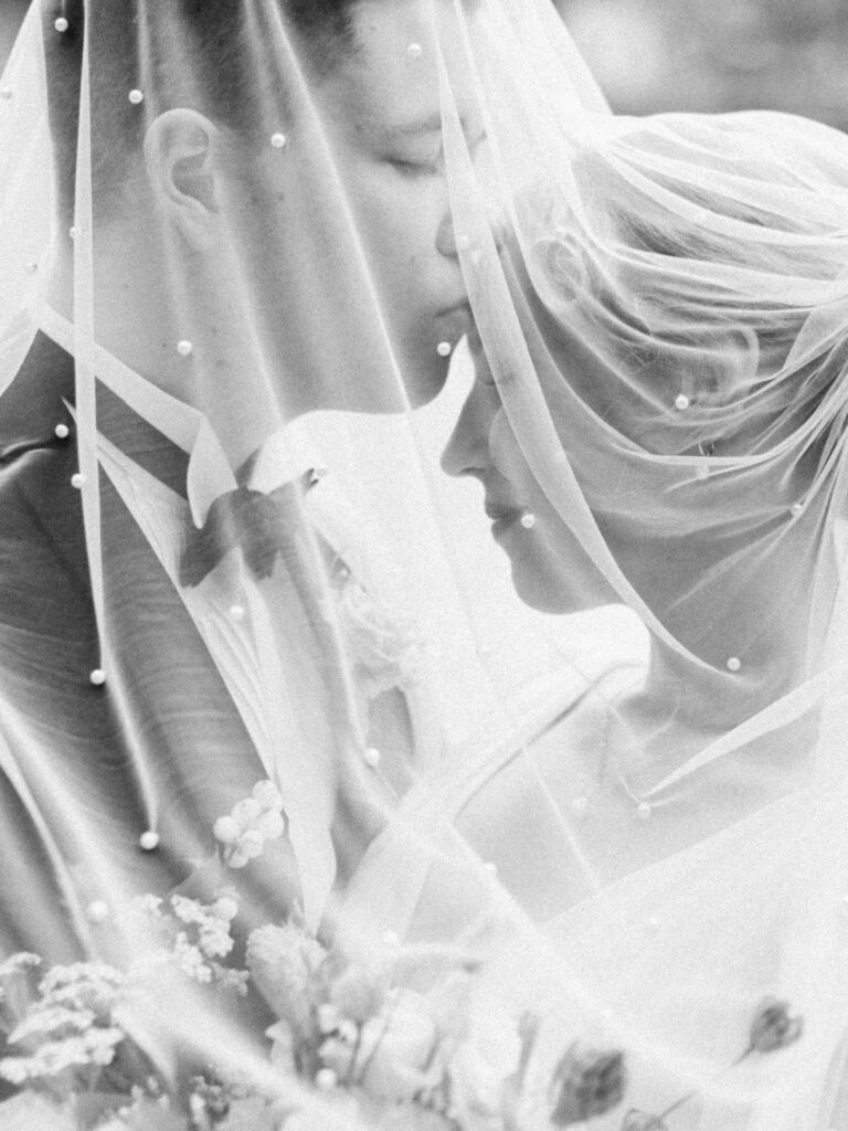 Hääpari kuvassa hunnun alla, suudelma